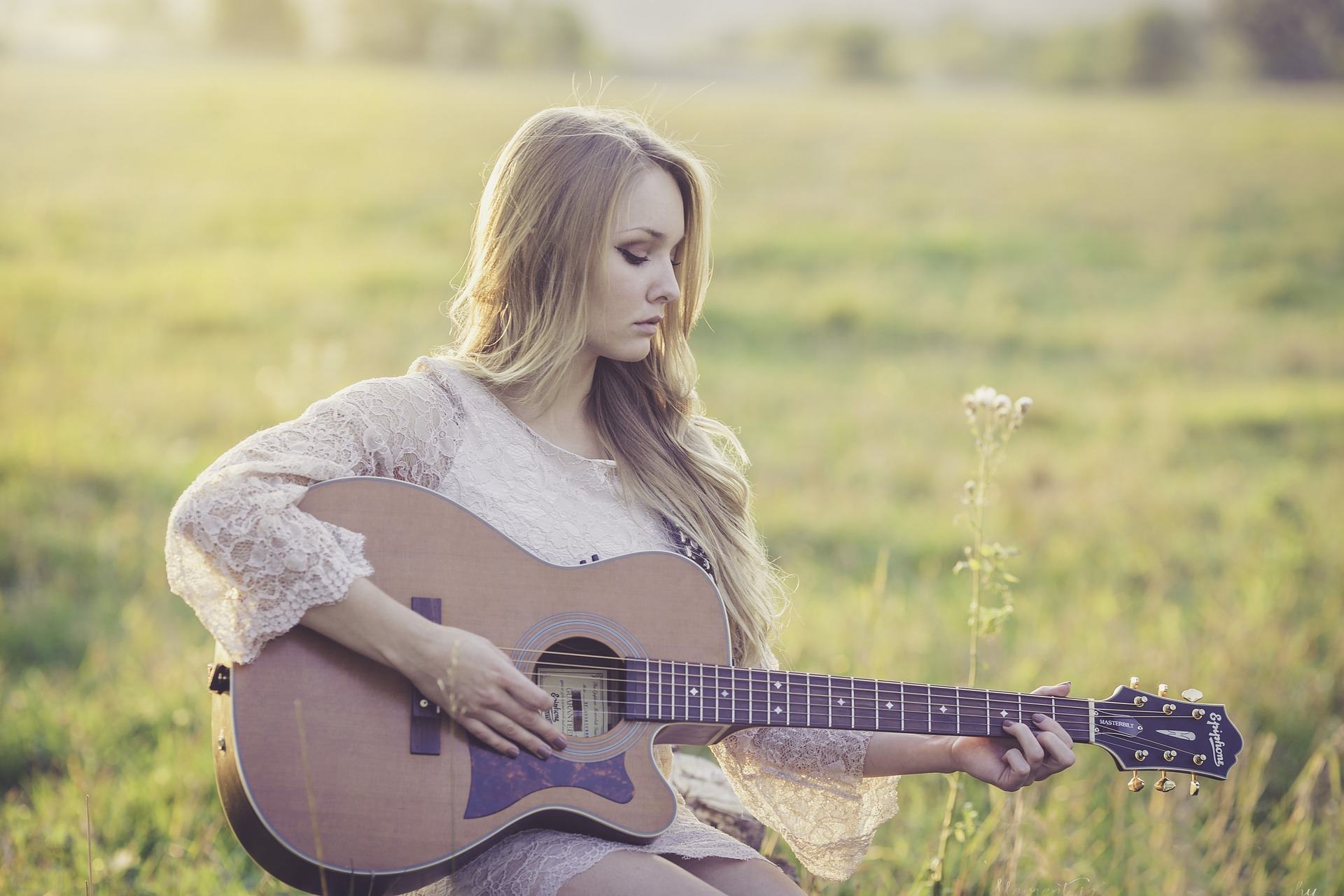 Eine junge Frau, die in der Natur Gitarre spielt